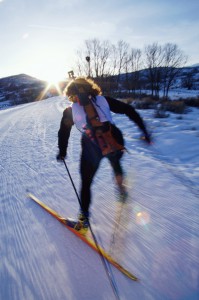 Female biathlete cross country skiing, rifle on back