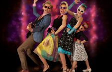 Rockabilly family band having fun posing with guitar and vintage microphone in 1950’s style clothing.